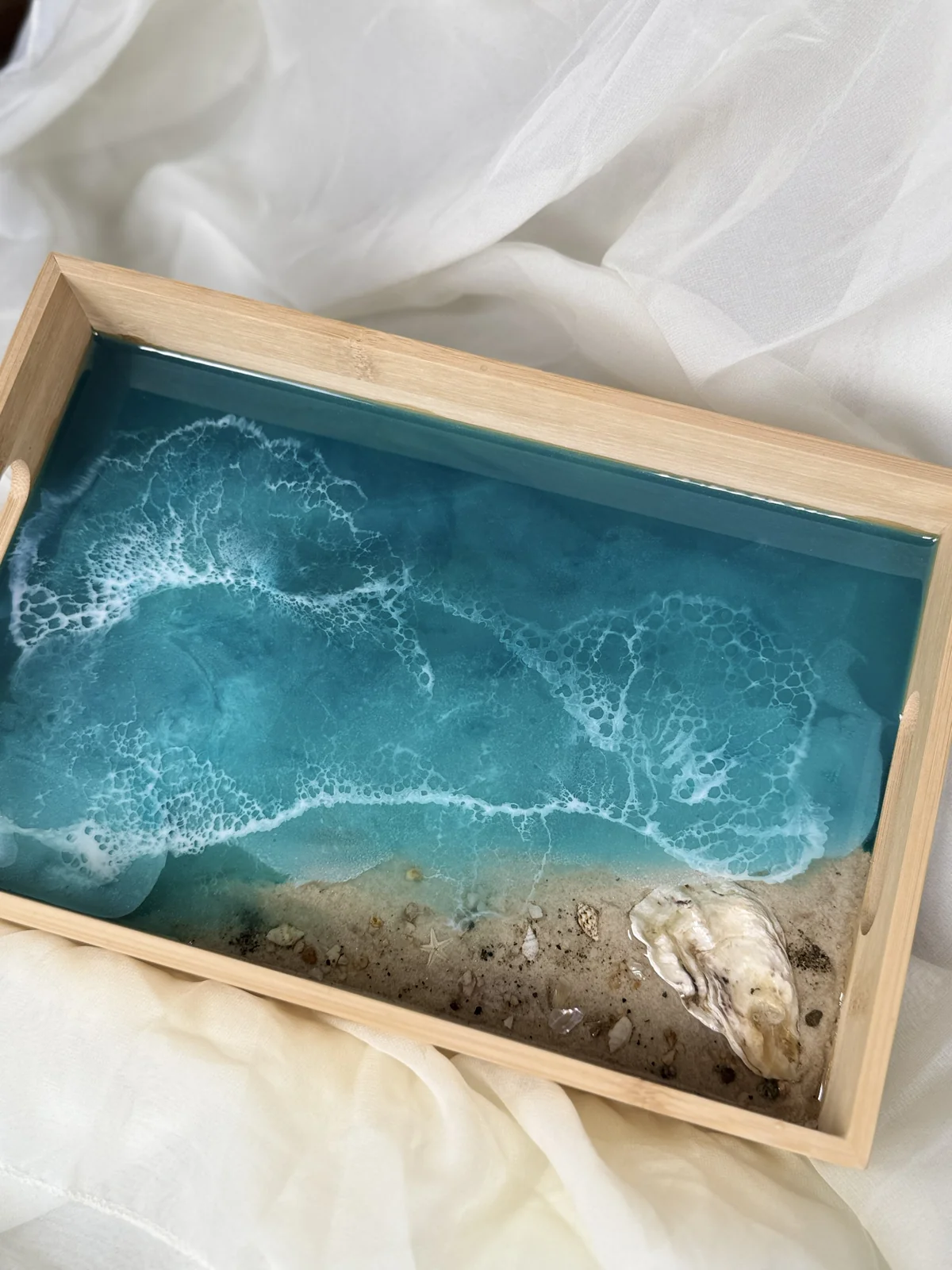 Wooden box with a coastline scene featuring waves crashing on the sandy beach and shells.