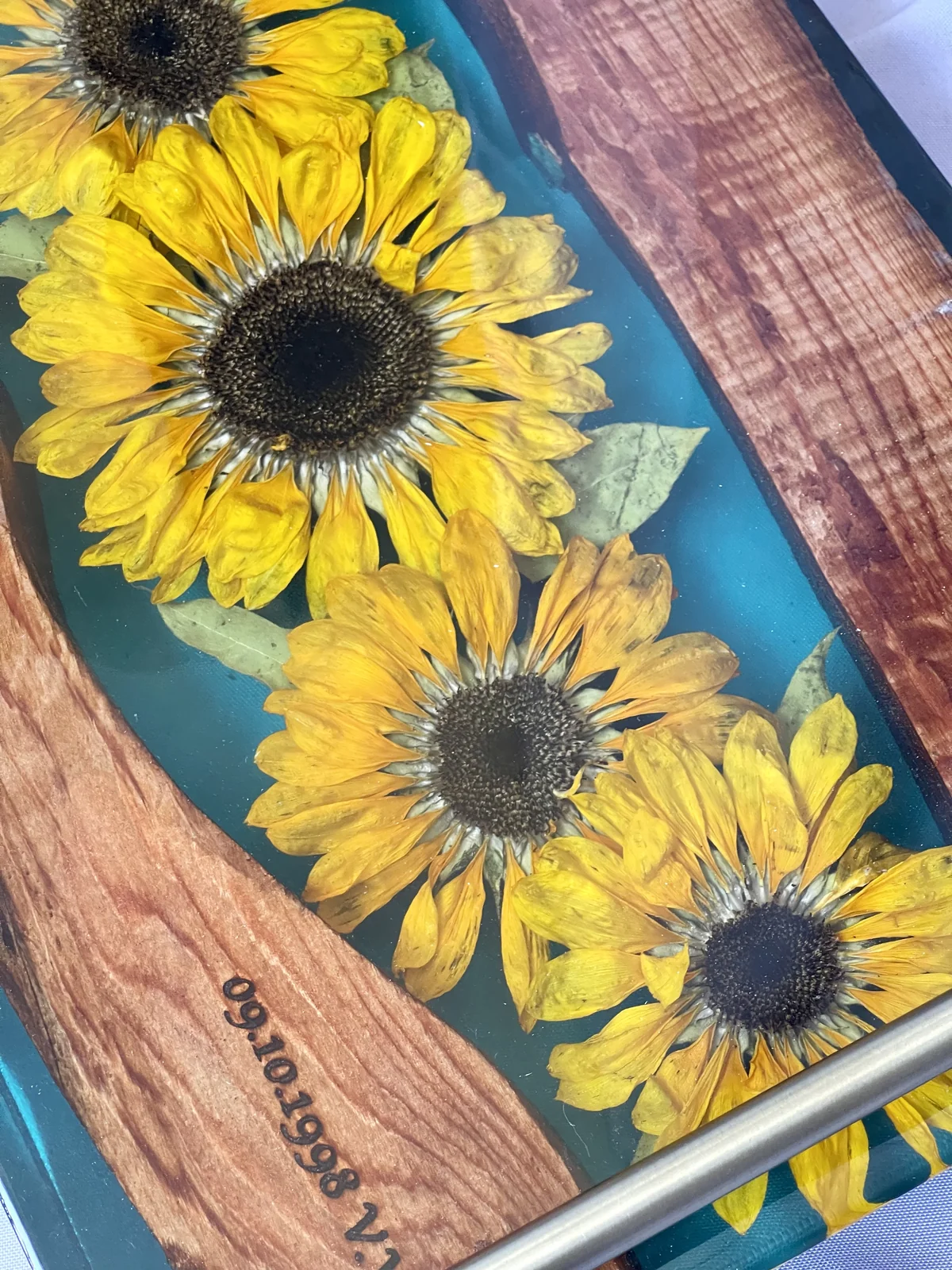 Three yellow sunflowers preserved in resin tray with driftwood.